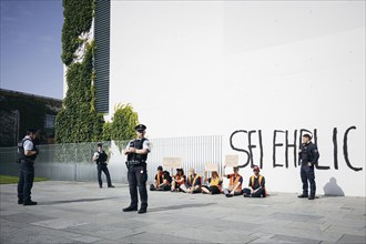 Demonstrators sit with signs in front of the Federal Chancellery, the demonstrators have written