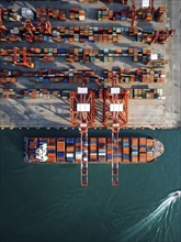 Aerial view of a cargo harbor with its geometric patterns of cranes and parked ships, AI generated