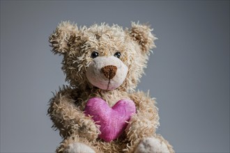 Teddy bear plush toy holding pink heart. Generative AI, AI generated