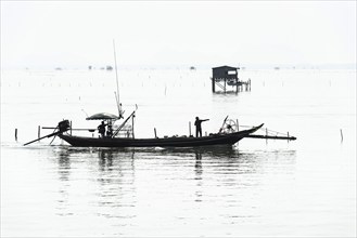 Traditional wooden huts of fishermen in the Gulf of Thailand in the morning haze, fishing boat,