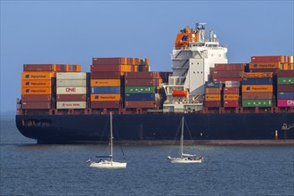 Sailboats sailing past stern of container ship, containership Hudson Express of the Hapag-Lloyd AG