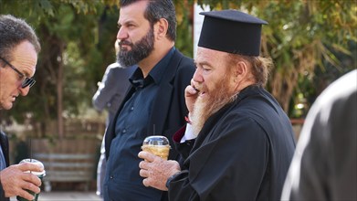 Men, including an Orthodox priest, drinking and chatting outdoors, visit of German President