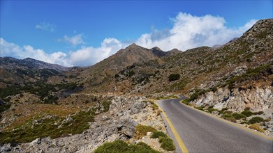 A winding road meanders through a rocky mountain landscape under a clear blue sky, Kallikratis,