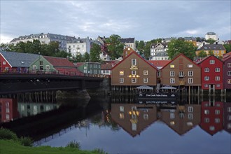 Colourful wooden houses reflected in the water in the evening, with bridge and historic city