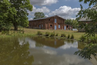 Former pigsty from 1920, in front the pond on an estate, Othenstorf, Mecklenburg-Vorpommern,