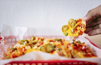 Hand taking nachos from a tray. Hand of people taking nachos on isolated background