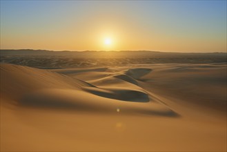 Sunset over a vast desert landscape with gentle sand dunes and clear sky, Matruh, Great Sand Sea,