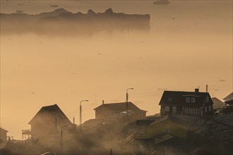 Inuit settlement in front of icebergs in the fog, midnight sun, summer, Ilulissat, Ilulissat