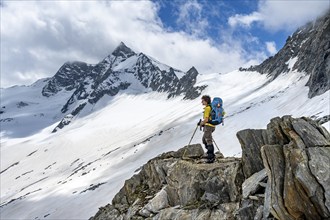 Mountaineer on a rock between snow, descent from the summit of Schönbichler Horn, view of