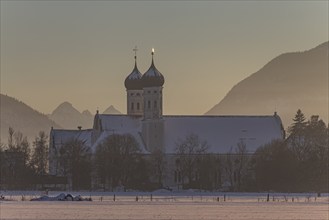 Monastery and basilica in the evening light in front of mountains, snow, winter, Benediktbeuern