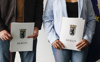 Berlin, 17.01.2023, Naturalised citizens show their naturalisation certificates after a