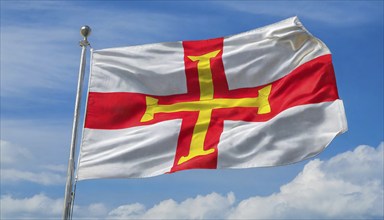 The flag of the Isle of Guernsey, Great Britain, flutters in the wind