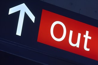 Red exit sign with white arrow pointing upwards, illuminated in a dark environment, Toronto