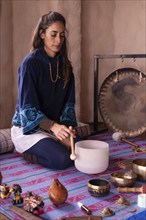 A lovely Latina woman sitting on her ankles, surrounded by sound instruments, engages in