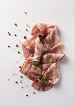 Raw bacon, sliced, with micro greenery and spices, on a white background, close-up