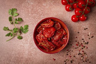 Dried tomatoes, in a bowl, top view, on a brown background