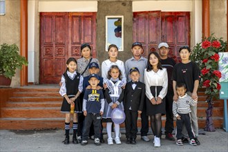 Family and school children, group posing in front of the school on the first day of school,