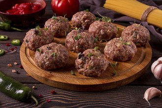 Raw meatballs, with micro greenery, with spices and ingredients, on a wooden table, homemade,