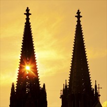 The sun shines through one of the two towers of Cologne Cathedral, Cologne, Rhineland, North