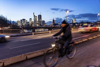 Skyline of the city centre of Frankfurt am Main, cyclist on the raft bridge, dusk, river Main,