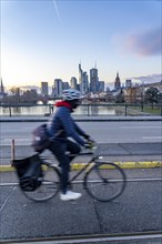 Skyline of the city centre of Frankfurt am Main, cyclist on the Ignatz-Bubis-Bridge, dusk, river