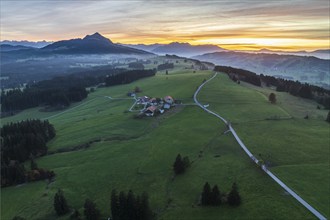 Mountain range near village Wertach, view to mt. Gruenten, sunset, fog in valley, traditional farm,