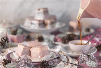 Coffee is poured into a pink cup, alongside cake, punch doughnuts and Christmas decorations