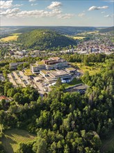 Aerial view of a town in green surroundings, many houses and a large building on a hill, blue