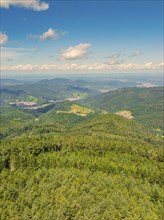 Panoramic view of densely forested mountains, partly sunny, partly cloudy under a blue sky,