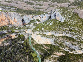 An impressive gorge with a river and steep cliffs surrounded by green vegetation, aerial view, Vero