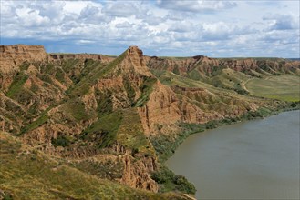 Eine weite Sicht auf einen grünen und braunen Canyon, der an einen ruhigen Fluss grenzt, Barrancas