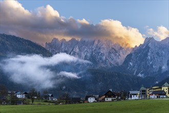 The houses of Gosau (Mittertal) with the Gosaukamm at sunset. Blue sky, bright clouds. Gosau, Gosau