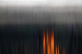 Abstract vertical lines with dark tones and orange-coloured accents, foggy mood over the water at