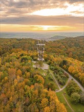 Observation tower in an autumnal forest landscape at sunset with colourful foliage and paths,