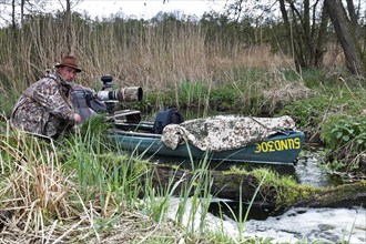 A canoe with camouflaged camera in a swamp, surrounded by vegetation and quiet nature, boat of a