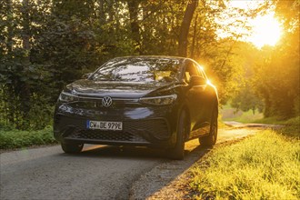 Car on a road in the forest in the evening light of the sunset, electric car, VW ID5, Gechingen,