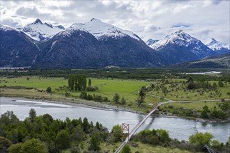 Old-style suspension bridge over river Rio Nadis south of Cochrane, snow-capped mountains at Rio