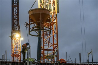 Concrete work, at dusk, on a large construction site building a residential and commercial complex,