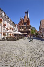 Historic town hall with outdoor area of the confectionery and café Leyhausen under a cloudless blue