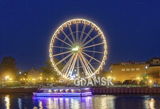 The Ferris wheel illuminated in the evening on the Motlawa, Motlawa, and the lettering Gdansk,