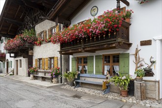 Typical Bavarian houses, balconies with geraniums, bench with figures, Frühlingstraße, Garmisch,