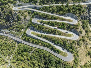 Mountain pass road with multiple hairpins, water pipeline, aerial view, drone shot. Valais,