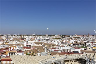 Sweeping views over the city with a hot air balloon on the horizon under a clear blue sky, Seville