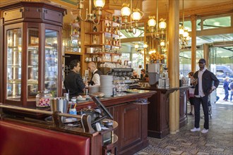 Elegant café with busy staff behind a glass-topped wooden counter, Paris