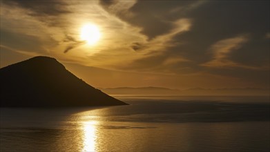 A silhouette of a mountain at sunrise with golden-coloured sea, Mani Peninsula, Peloponnese,