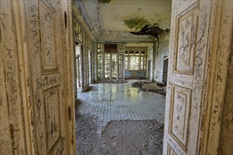 Abandoned building with large windows and dirty tiles, the dilapidated interior has clear signs of