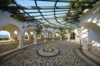 A bright, Mediterranean-inspired courtyard with cobblestones and climbing plants, overlooking the