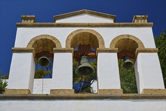 Cross-domed church of Diasososuan, white bell tower with three arches and hanging bells against a