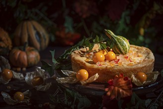 An autumnal cake decorated with yellow physalis and pumpkin in a romantic atmosphere