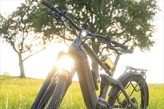 E-bike in a meadow, the evening sun shines on the bike and creates a luminous scenery, forest bike,